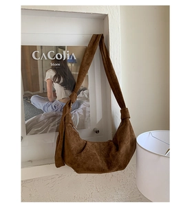 Detail of soft brown suede dumpling bag with wide knotted strap and pleated texture
