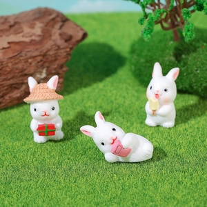 Three cute resin rabbits with gift boxes and snacks in a forest miniature landscape scene