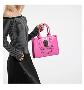 Detailed side view of pink tote bag with black skull metal and studded decorations