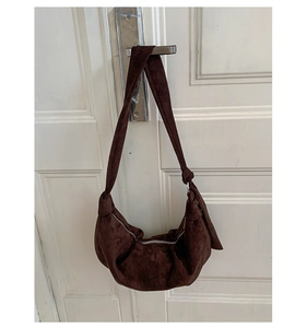 Detailed view of coffee brown suede crescent hobo bag hanging on a white door handle
