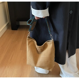 Detail of suede bucket bag with colorful ethnic style embroidered wide strap for women