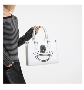 Detailed view of white tote bag featuring a 3D crystal skull and grey stud embellishments