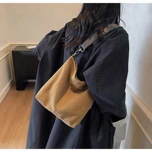 Detail of a brown suede bucket bag featuring a wide ethnic style patterned shoulder strap