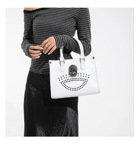 Détail d'un sac cabas blanc avec ornement crâne métallique et rivets gris décoratifs