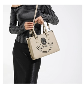 Gros plan du sac cabas beige avec crâne en strass et clous métalliques argentés