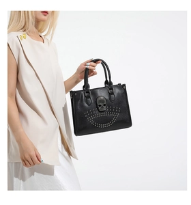 Détail d'un sac à main gothique noir orné d'un grand crâne en métal et de rivets