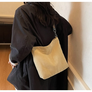 Detail view of spacious beige hobo bucket bag with ethnic embroidered wide strap and matte texture