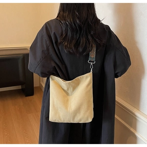 Detail of beige canvas bucket bag with vintage pattern wide strap shown in lifestyle setting