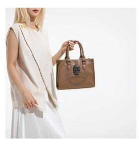Détail macro d'un sac cabas en cuir marron avec crâne en métal 3D et rivets argentés décoratifs
