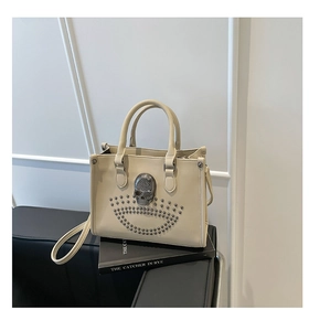 Détail du sac en cuir crème orné d'un crâne métallique 3D et de rivets argentés