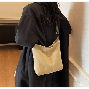 Detail of beige corduroy tote bag with ethnic woven shoulder strap and metal hooks