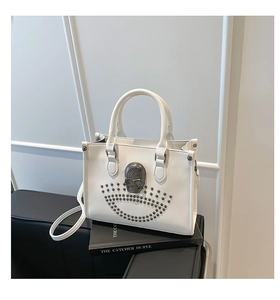Détail d'un cabas en cuir blanc orné d'un crâne en métal vintage et de rivets cloutés