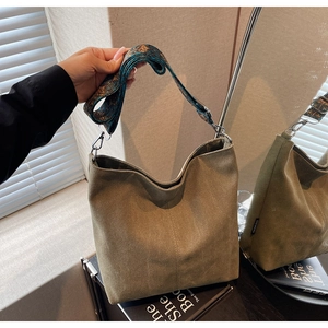 Detailed view of canvas bucket bag with ethnic embroidered strap and green fabric texture