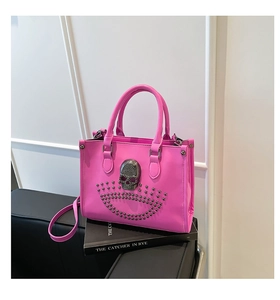 Détail d'un sac cabas en cuir rose vif avec crâne argenté et rivets métalliques ronds