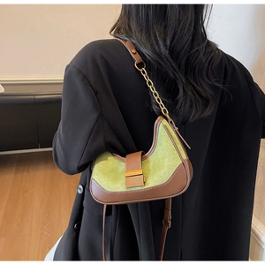 Detail of green and brown half-moon underarm bag with gold chain strap on black blazer