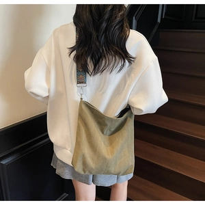 Rear view of model wearing a khaki canvas bucket bag with ethnic woven shoulder strap