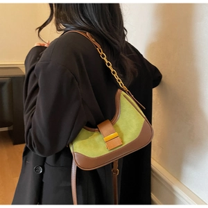 Detail of green suede moon bag with brown leather trim and golden metal chain strap