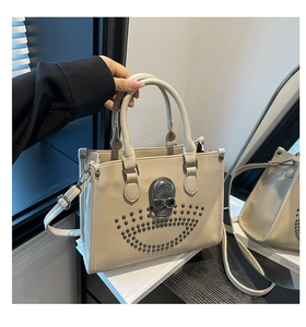 Détail d'un sac punk beige avec un crâne en strass et des accents de rivets en métal