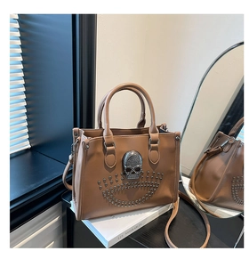 Détail d'un sac cabas en similicuir marron avec tête de mort et rivets métalliques