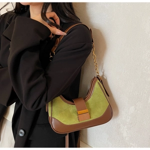 Green suede and brown leather saddle bag styled with a black blazer on a model