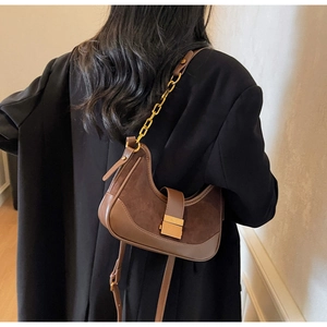 Detail of dark brown crescent hobo bag with gold chain strap and stylish contrast paneling