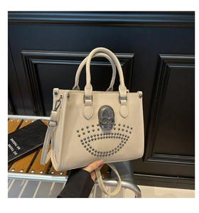 Détail du sac fourre-tout blanc crème avec logo de crâne et rivets métalliques argentés