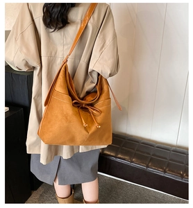 Close-up of vintage brown suede tote bag featuring bow tie detail and white topstitching