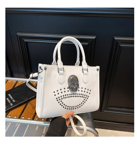 Détail d'un sac cabas blanc punk avec un crâne en métal argenté et des rivets décoratifs
