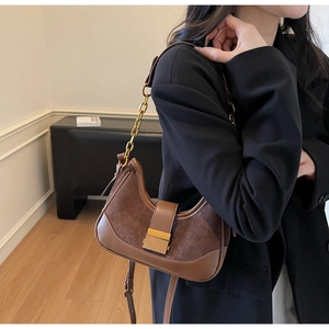 Detail of a brown patchwork shoulder bag featuring leather and suede texture with gold chain