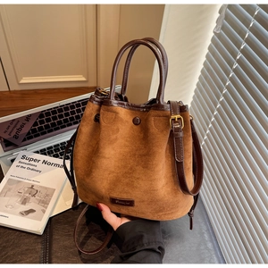 Gros plan détaillé du sac seau en daim marron avec poignées en cuir et cordon de serrage