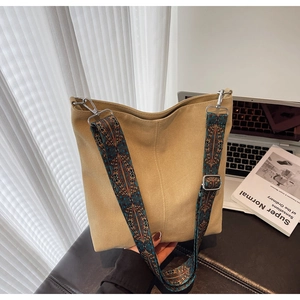 Close-up of khaki canvas bucket bag featuring a vintage ethnic patterned wide shoulder strap