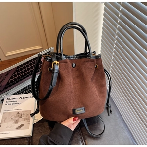 Vue détaillée du sac seau en daim marron avec bordure en cuir noir et cordon de serrage