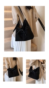 Detail of black canvas bucket bag featuring white contrast stitching and bow drawstring