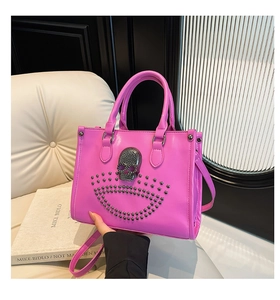 Détail du sac à main fuchsia en cuir verni avec tête de mort et rivets métalliques argentés