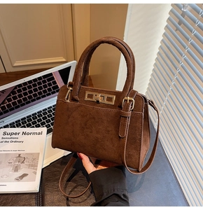Detail of dark brown suede tote bag with golden metal twist lock and dual handles