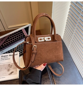 Detail of dark brown suede tote bag with metal clasp and structured trapezoid design