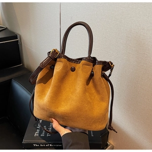 Détail du sac seau en daim jaune vintage avec cordon et bandoulière en cuir marron foncé