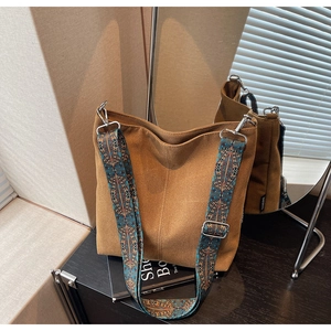 Detail of vintage canvas bucket bag featuring a colorful jacquard woven shoulder strap