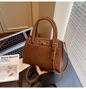 Detailed macro view of dark brown suede handbag featuring golden square lock and leather straps