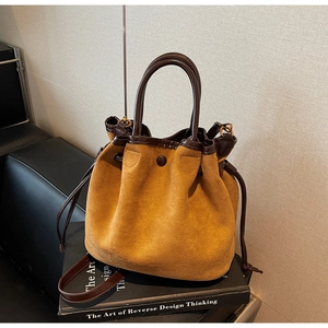Détails de ce sac seau en daim camel avec bordures en cuir marron et fermeture à cordon