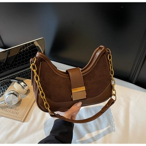 Close-up of brown hobo bag with gold buckle, metal chain, and stylish suede patchwork detail