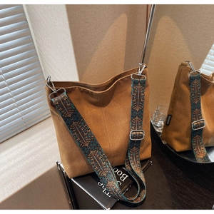 Detail view of brown canvas bucket bag with ethnic geometric pattern wide strap