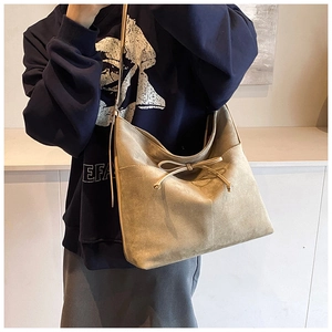 Detail shot of khaki suede tote bag featuring a decorative drawstring bow and soft texture