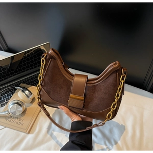 Detail view of retro brown shoulder bag with leather stitching and gold metal chain