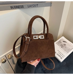 Detail shot of a dark brown suede tote bag with a metal turn-lock and adjustable strap