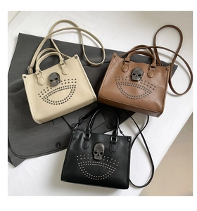 Détail de sacs cabas à clous avec breloques crâne en beige, marron et noir