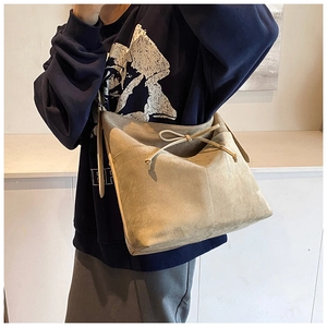 Détail d'un sac cabas en daim beige avec un nœud décoratif et une texture mate douce