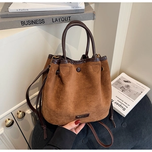 Détails de la texture en daim sur un sac seau rétro avec cordon en cuir marron