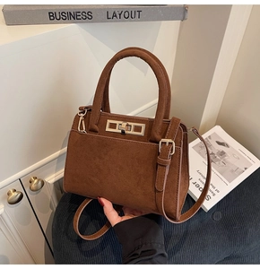 Close-up of brown suede handbag featuring a vintage gold twist lock and fine texture