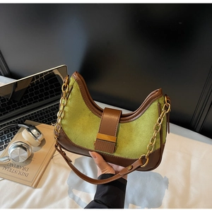 Detail of green suede shoulder bag with brown leather trim and retro gold chain strap